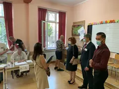 Избирателна секция в класна стая в София: членове на комисията на маса, гласоподаватели и наблюдатели с маски